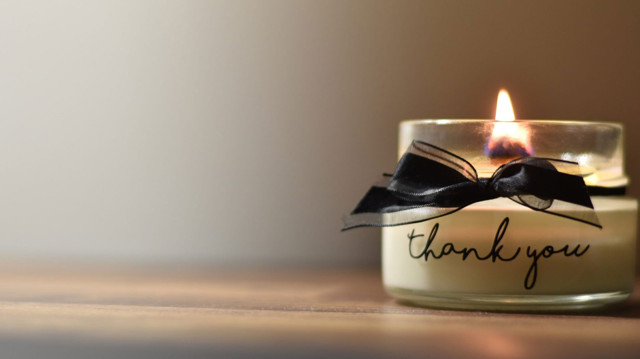 A candle in a jar which says Thank You on the outside