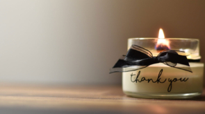 A candle in a jar which says Thank You on the outside