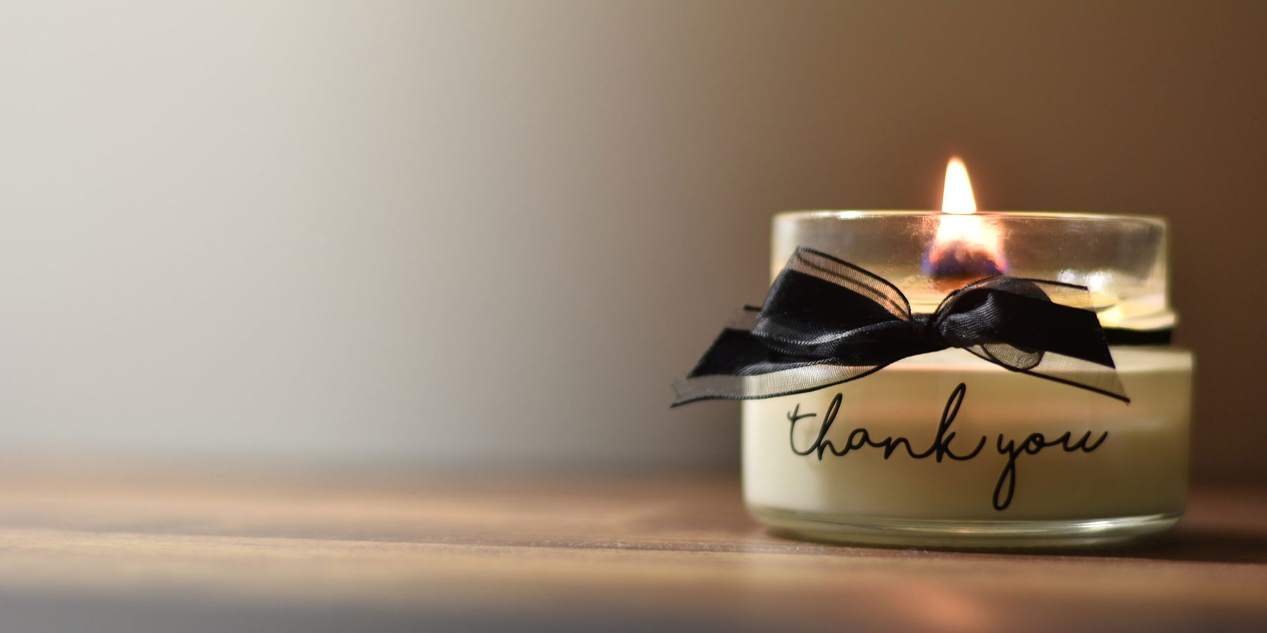 A candle in a jar which says Thank You on the outside