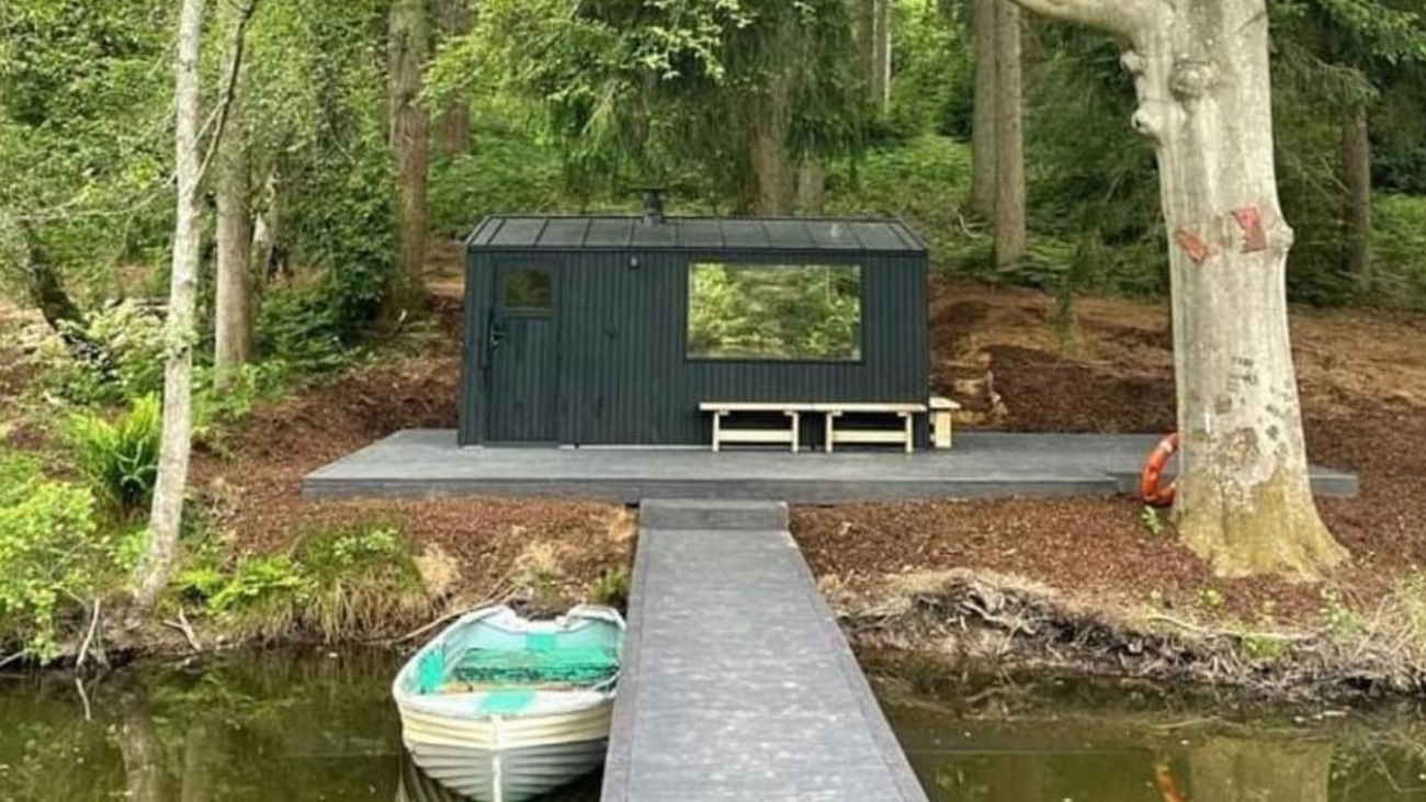 A boat house, pontoon and rowing boat at the side of a lake