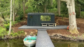 A boat house, pontoon and rowing boat at the side of a lake