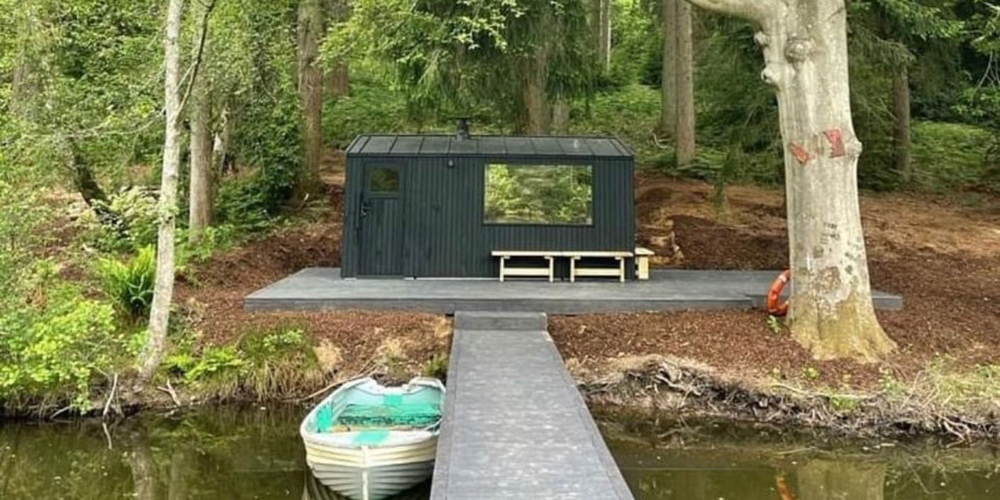A boat house, pontoon and rowing boat at the side of a lake