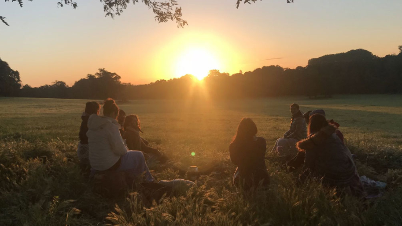 Group sat in a field watching the sunset