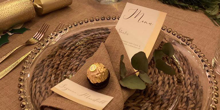 Dinner setting with a personalised name card with a napkin folded around it