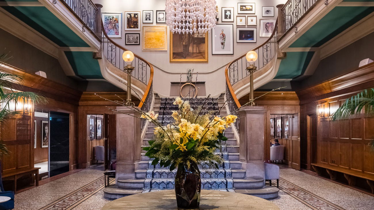 Entrance hall with double staircase with a table in the centre and a vase of flowers