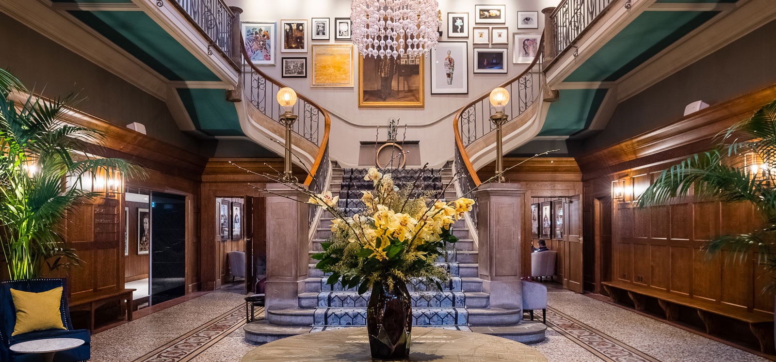 Entrance hall with double staircase with a table in the centre and a vase of flowers