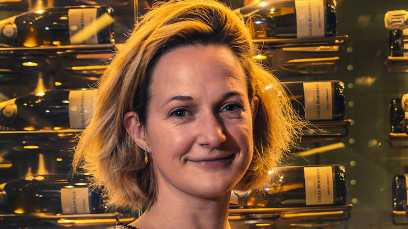 Photo of Lucy stood in front of a display of red wine bottles