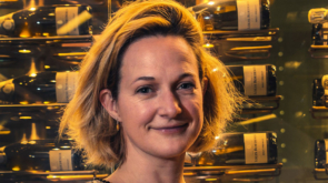 Photo of Lucy stood in front of a display of red wine bottles