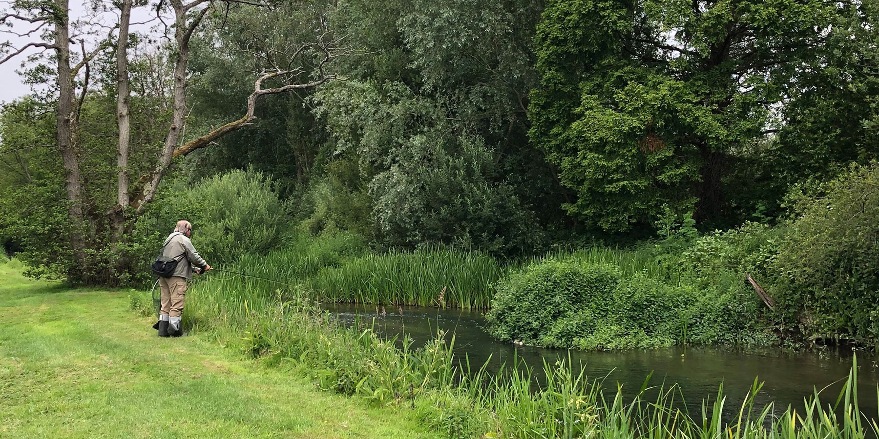 A man fishing at the side of the river