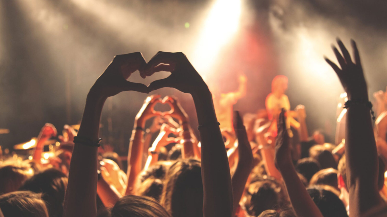 Person making a heart shape with their hands at a concert