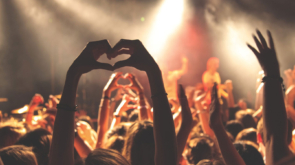 Person making a heart shape with their hands at a concert