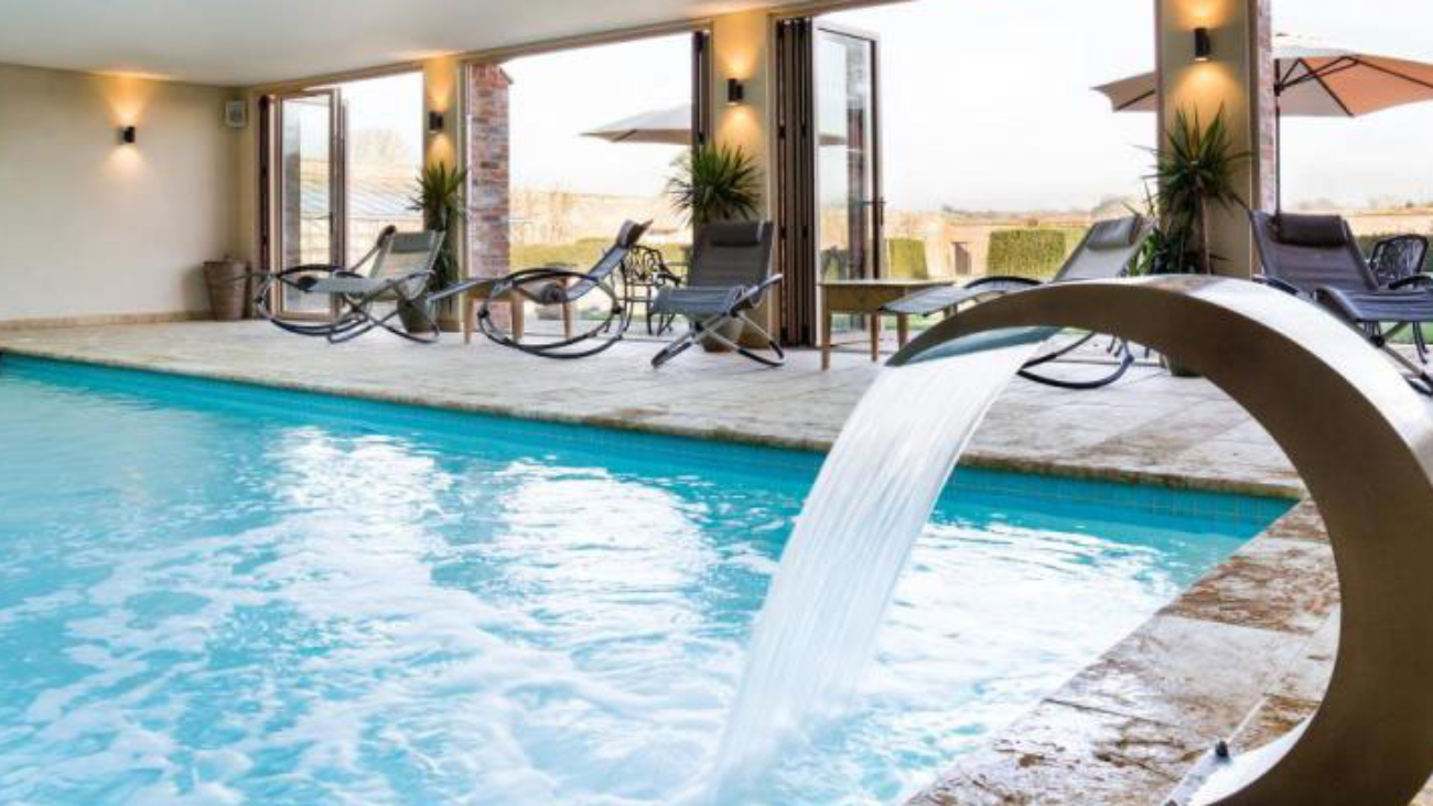 View of a pool at a spa with loungers leading out to a terrace