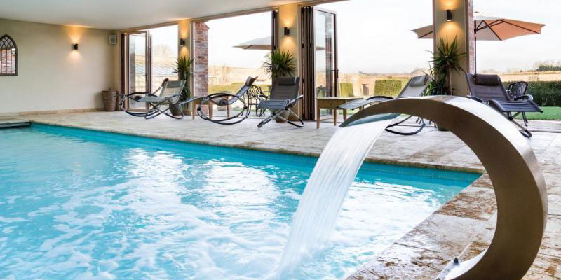 View of a pool at a spa with loungers leading out to a terrace
