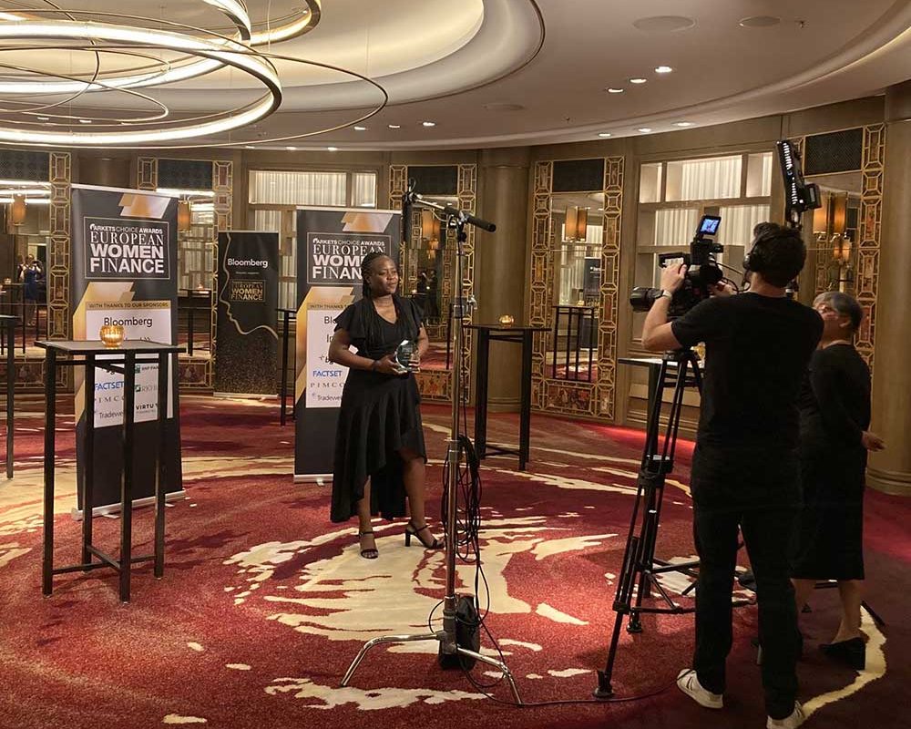 Woman collecting an award and stood infront of cameras