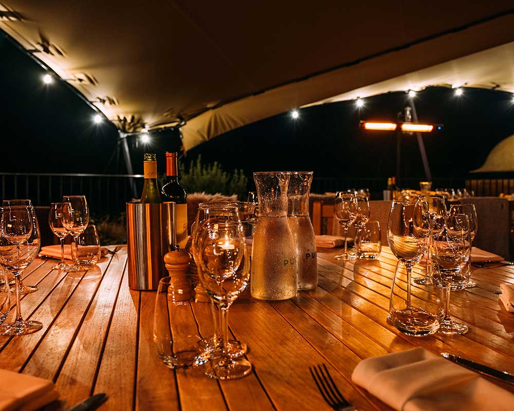 A table set up with wince on an evening under a marquee