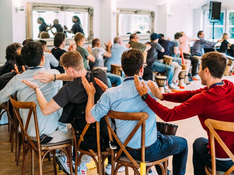 Group of people taking part in a bongo drum workshop at a founder Retreat